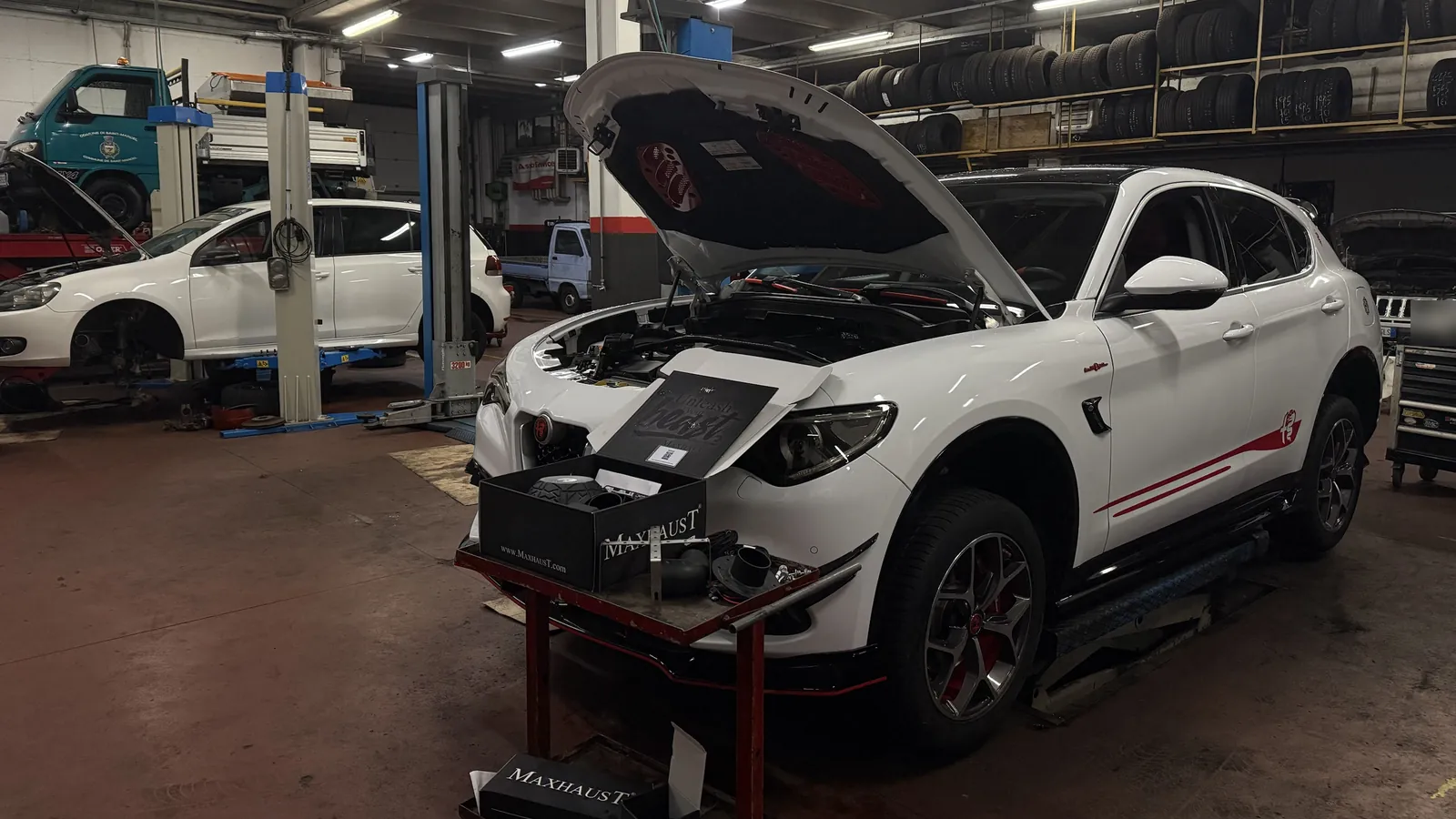 Alfa Romeo Stelvio in officina con il cofano aperto e il kit active sound Maxhaust pronto per il montaggio
